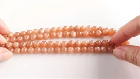 Sparkling orange gemstone beads arranged neatly on thin threads Stock Footage 345139714