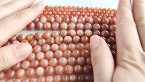 Sparkling orange gemstone beads arranged neatly on thin threads Stock Footage 345139736