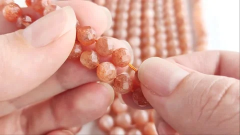 Sparkling orange gemstone beads arranged neatly on thin threads Stock Footage 345139754