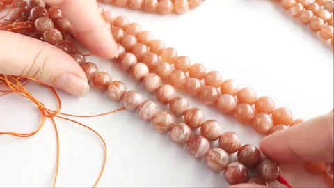 Sparkling orange gemstone beads arranged neatly on thin threads Stock Footage 345139771