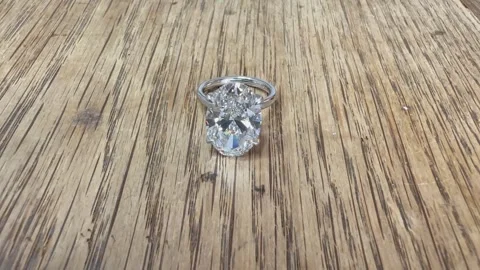 Sparkling oval diamond platinum ring on rustic wood in daylight Stock Footage 314895295