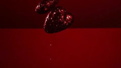 Sparkling red hearts falling and bouncing on reflective surface Video stock 327631665