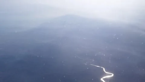 Sparkling river winding through misty landscape from above during a flight Stock Footage 339353816