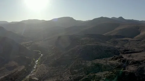 A sparkling stream cuts through a deep valley in a barren desert at sunset. Stock Footage 127019237