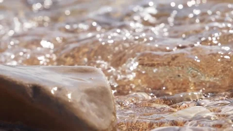 Sparkling sunlight glimmers on clear water flowing over wet rocks. Stock Footage 337409981