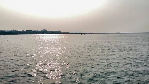 Sparkling sunlight reflection on calm sea water surface with distant coastline Stock Footage 343140848