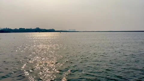 Sparkling sunlight reflection on calm sea water surface with distant coastline Stock Footage 343140855