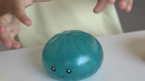 Sparkling teal squishy dumpling toy sits alone on white table showing cute Stock Footage 345653459