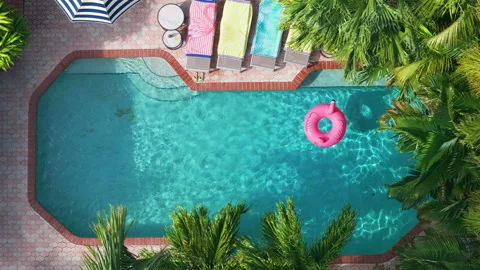 Sparkling tropical pool with flamingo float, loungers and red roof house Vidéo 305803456