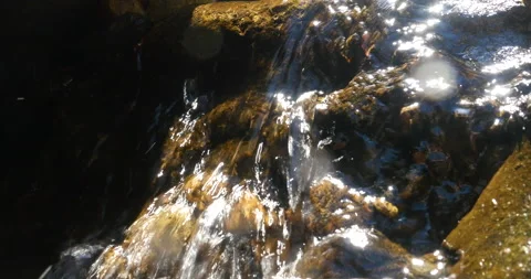 Sparkling Water Stream Running Over Rocks With Dappled Light From Sun highlights Stock Footage 138410923