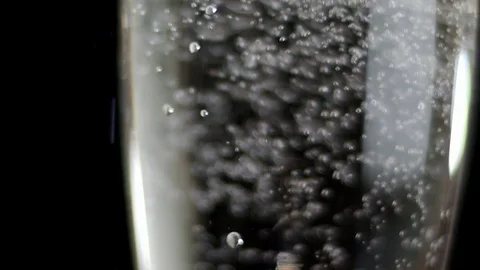 Sparkling of white wine. White wine being poured into a glass of black Stock Footage