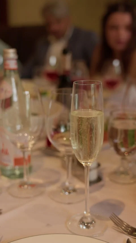 Sparkling wine flute on banquet table with soft blurred guests and elegant Video stock 345263916