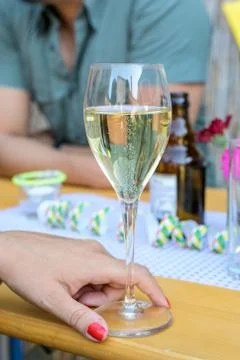 Sparkling wine in glass with hand in restaurant or wedding party dinner setti Stock Photos