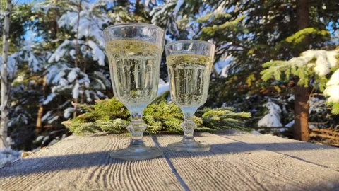 Sparkling wine in two glasses on rustic wooden table with winter forest trees Stock Footage 196241515