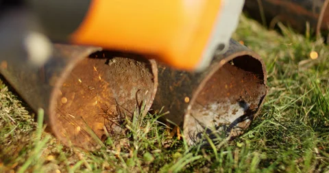 Sparks from an angle grinder fly onto the grass on a sunny summer day in slow Stock Footage 314979305