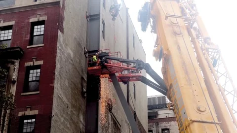 Sparks construction site crane man hardhat working building New York City NYC Stock Footage 254380104