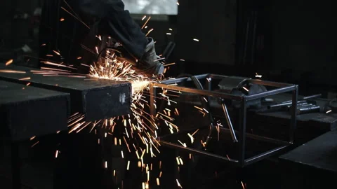 Sparks from the electric grinder tool fly out from under the hands of the Stock Footage 135747433