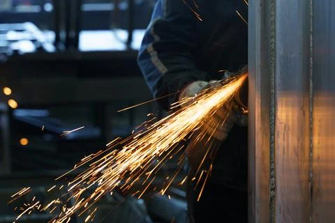 Sparks fly as a skilled worker performs metal grinding in a workshop Stock Photos