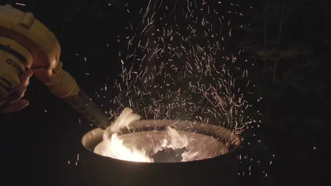Sparks flying dramatically from the firepit in a dark setting Stock Footage 280688478
