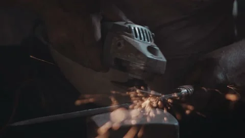 Sparks flying towards camera from a grinder sharpening a metal piece Stock Footage 143610179