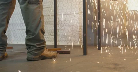 Sparks from metal grinder fall at workman's boots Stock Footage 56864745