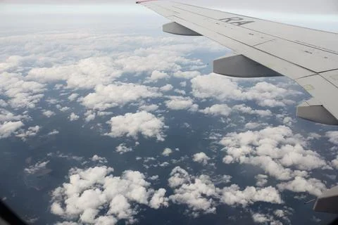 Sparse clouds under the wing of an airplane. 库存照片