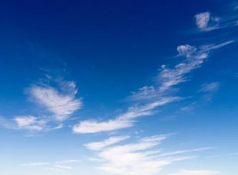 Sparse, wispy clouds in a bright, blue sky Foto stock