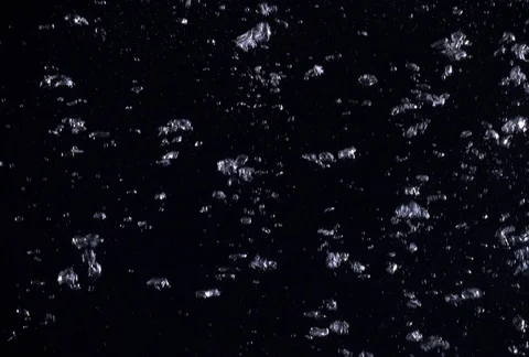 Sparsely concentrated tiny bubbles forming larger masses as they rise in dark Stock Footage 86919473