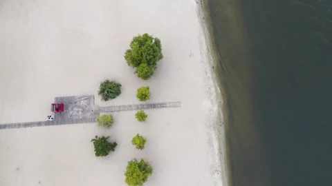 A sparsely populated white sand beach surrounded by trees and clear waters of Stock Footage 194013471