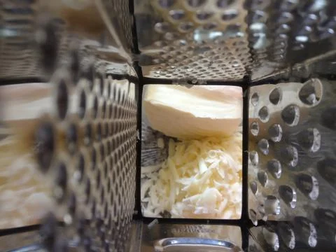 Spatial view from grater towards cheddar cheese Stock Photos