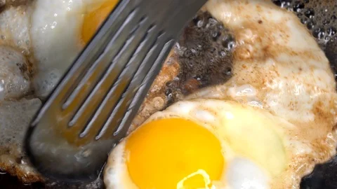 Spatula cuts and flips sizzling fried egg closeup macro Stock Footage 111118074