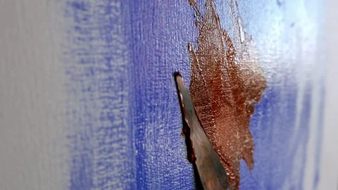 Spatula extends red oil on a canvas painted blue Stock Footage 80859653