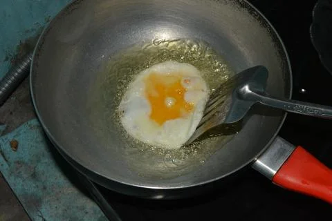 Spatula lifting fried egg while cooking in pan Stock Photos