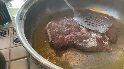 Spatula prepares hot steaming beef dish for cooking on kitchen stove top. Video stock 129844033