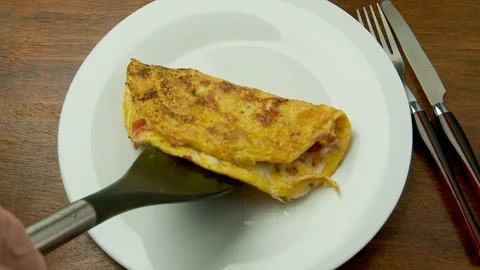 Spatula serves omelette to a white dinner plate Vidéo 128450424