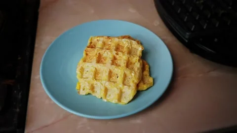 Spatula stacks finished waffles on blue plate on kitchen table Stock Footage 231527575