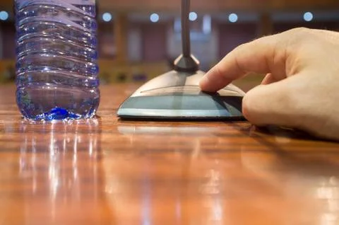 Speaker hand pressing on-off button of a table conference microphone Stock Photos