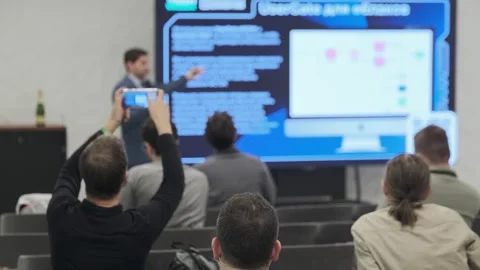 Speaker presents beside large digital display showing code and c Video stock 323133699