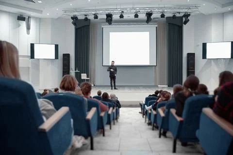 Speaker standing near the big screen during a business seminar. Stock Photos