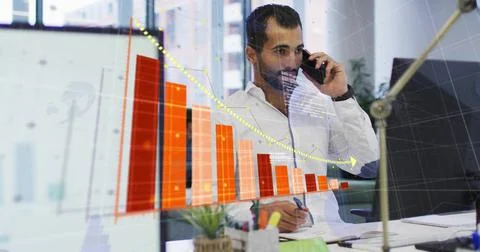 Speaking Middle Eastern man in white shirt holding phone taking notes at office Stock Photos