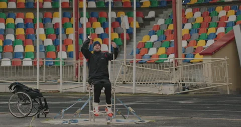 Spear throwing training Paralympian man with defective legs sitting in a Stock Footage 154250390