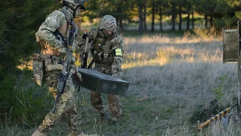 Special forces soldiers in full combat uniform, weapon on a mission. taking box Stock Footage 127857650
