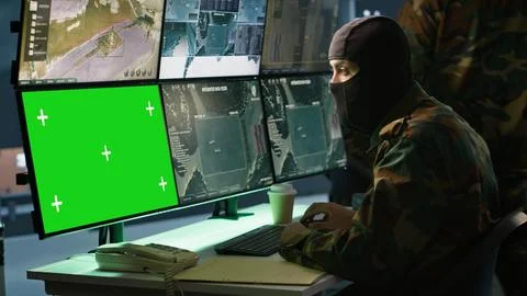 Special forces spy examining data in monitoring room with chroma key monitors Foto stock