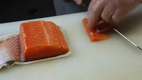 A special knife glides through the fresh salmon as the chef creates even slices  Stock Footage 284703214