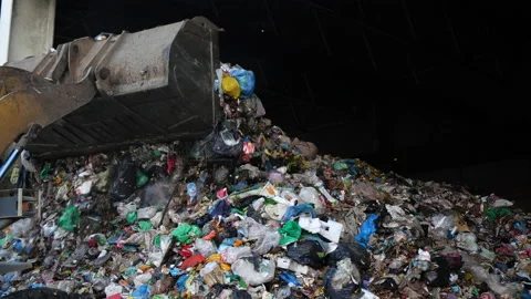 A special machine with a bucket heaps a pile of unsorted garbage. Stock Footage 145718934