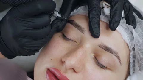 A special needle tattoo machine makes permanent makeup correction of a young 動画素材 166583037