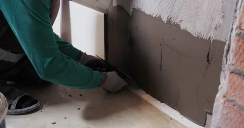 With special ribbed trowel, builder puts mortar on wall, smoothes, lay tiles Stock Footage 130366766