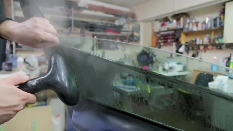 Specialist in an auto service workshop removing old sun protection tint film Stock Footage 337537891