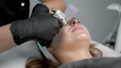 The specialist cleans the face of a lady with the help of the oxygen procedure Video stock 228567187