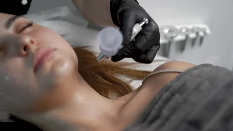 The specialist cleans the face of a lady with the help of the oxygen procedure Stock Footage 228567557